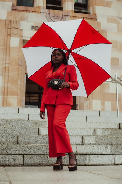 一个穿着红外套和裤子拿着伞的女人